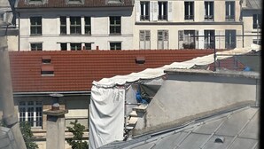 Eine Stadtansicht mit einem markanten historischen Gebäude im Hintergrund, umgeben von Wohnhäusern mit unterschiedlichen Dächern.