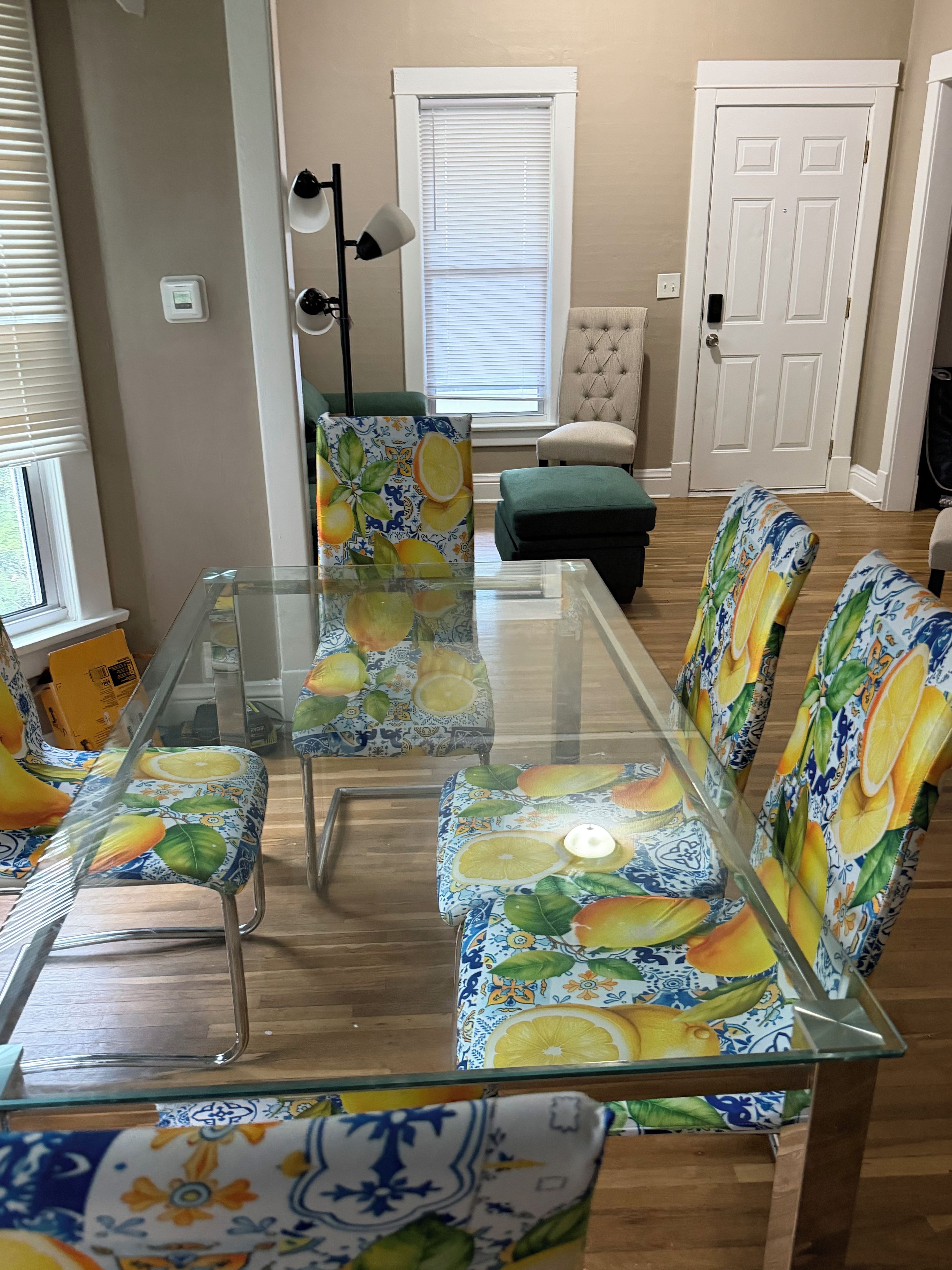 A dining area with a glass-top table and chairs with citrus fruit patterns.