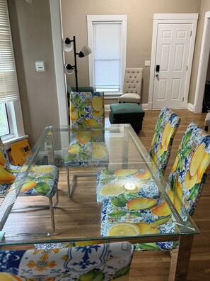 A dining area with a glass-top table and chairs with citrus fruit patterns. - Fantastic 3-bedroom house with AC in charming Benson Omaha (Omaha)
