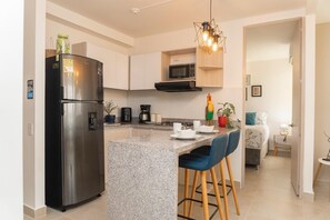 Una cocina moderna con un refrigerador de acero inoxidable, un microondas y una encimera de granito.