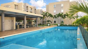 A swimming pool with a covered area, palm trees, and a building with balconies. - Escape to Cartagena and relax at Azul Sereno (Bolivar)