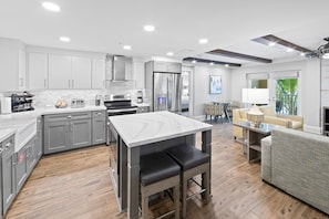 A modern kitchen with grey cabinets, a marble countertop, and a central island with seating. - Spacious 4BR Villa Near Beach & Access to Pools (Cape Canaveral)