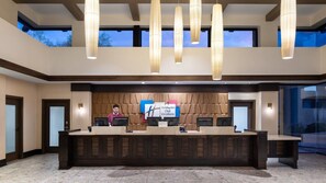 Un área de recepción con un mostrador de madera, dos monitores de computadora y un cartel de Holiday Inn Club Vacations.