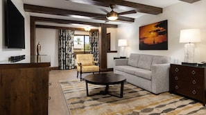 Sala de estar com sofá, poltrona, mesa de centro e ventilador de teto.
