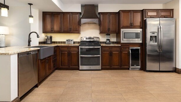 Una cocina con armarios de madera oscura, electrodomésticos de acero inoxidable, lavavajillas y microondas.