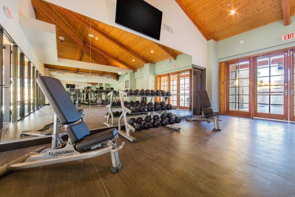Ein Fitnessstudio mit Laufbändern, Gewichtbänken und Kurzhanteln.