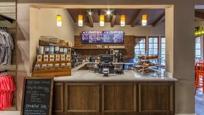 Een koffiehuis met een houten toonbank, een menubord en diverse koffie- en etenswaren.