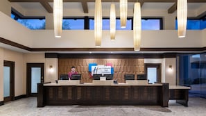Un área de recepción con un mostrador de madera, dos monitores de computadora y un cartel de Holiday Inn Club Vacations.