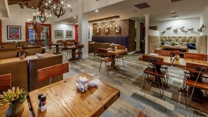 A spacious restaurant with wooden tables and chairs, a brick wall, and hanging lights. - Large 2BR Scottsdale Villa w/ Kitchen & Balcony (Scottsdale)