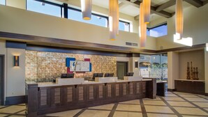A reception desk with a stone wall backdrop, a large window, and a tiled floor. - Large 2BR Scottsdale Villa w/ Kitchen & Balcony (Scottsdale)