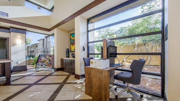 A modern office space with a large window, a desk with a computer, and a chair. - Large 2BR Scottsdale Villa w/ Kitchen & Balcony (Scottsdale)