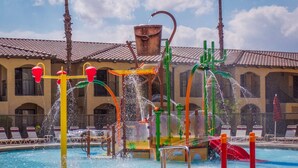 A water play area with multiple water jets and slides, a pool, and a building with arches in the background. - Large 2BR Scottsdale Villa w/ Kitchen & Balcony (Scottsdale)