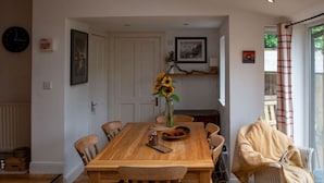 Ein Essbereich mit einem Holztisch, Stühlen, einer Vase mit Sonnenblumen und einem gerahmten Bild an der Wand.