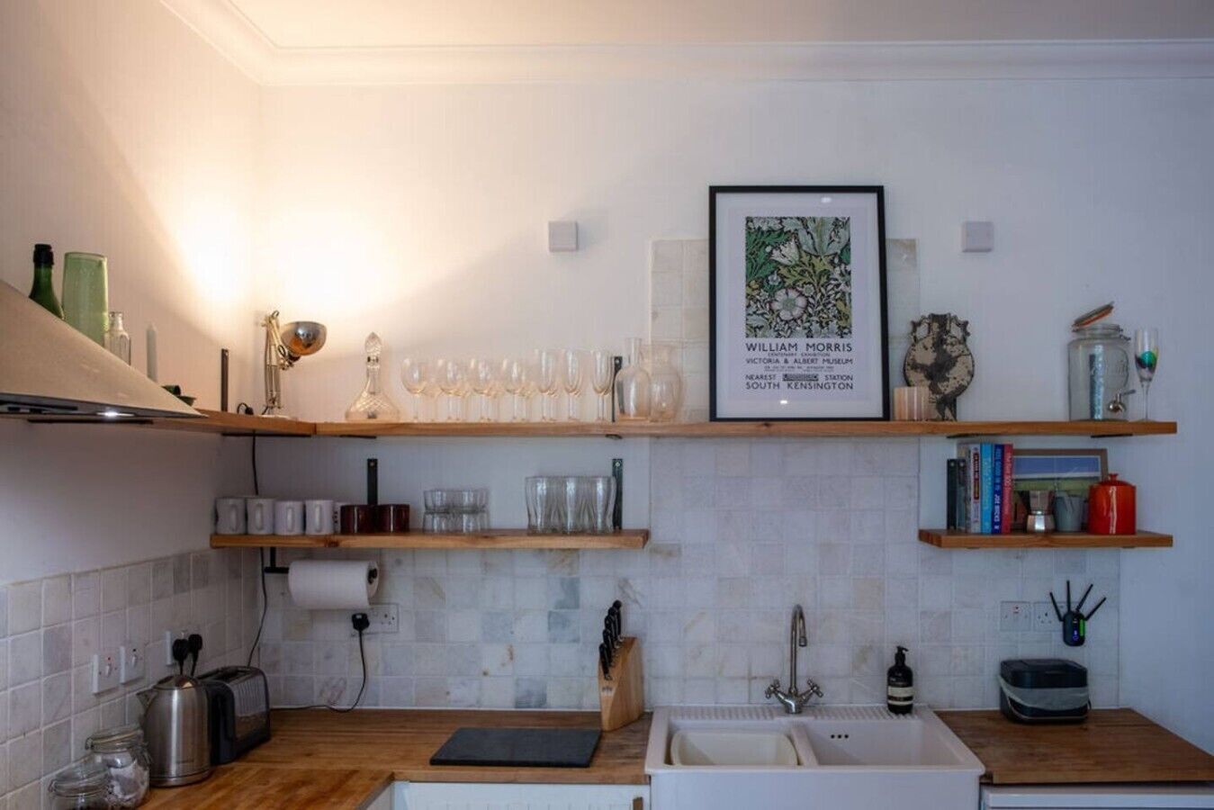 A kitchen with wooden shelves, a framed picture, and various kitchen items.