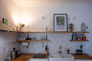Une cuisine avec des étagères en bois, un tableau encadré et divers ustensiles de cuisine.