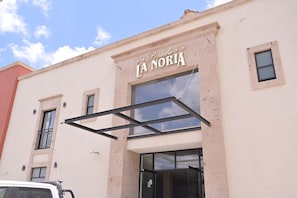 Un edificio con un cartel que dice 'Posada La Noria' y una entrada de vidrio.