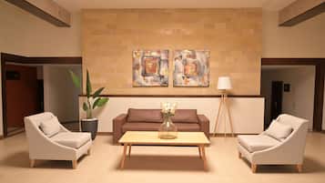 A lobby with two sofas, a coffee table, a floor lamp, and two potted plants.