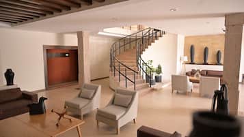 Un hall d’entrée moderne avec un escalier, un espace salon et un comptoir d’accueil.