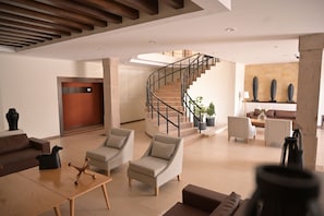 Un vestíbulo moderno con una escalera, zona de estar y mostrador de recepción.