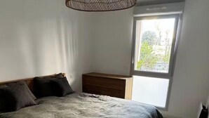 Et soveværelse med en seng, et natbord, en kommode og et vindue.