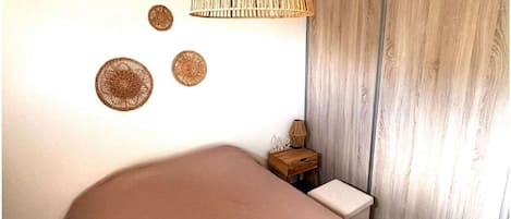 A bedroom with a bed, a hanging light fixture, a bedside table, and a wall with decorative plates.