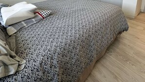 Un dormitorio con cama, estantería, armario y repisa de pared con objetos decorativos.