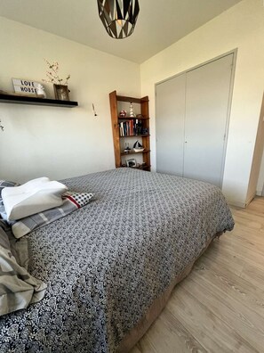 Ein Schlafzimmer mit einem Bett, einem Bücherregal, einem Kleiderschrank und einer Wandablage mit Dekoration.
