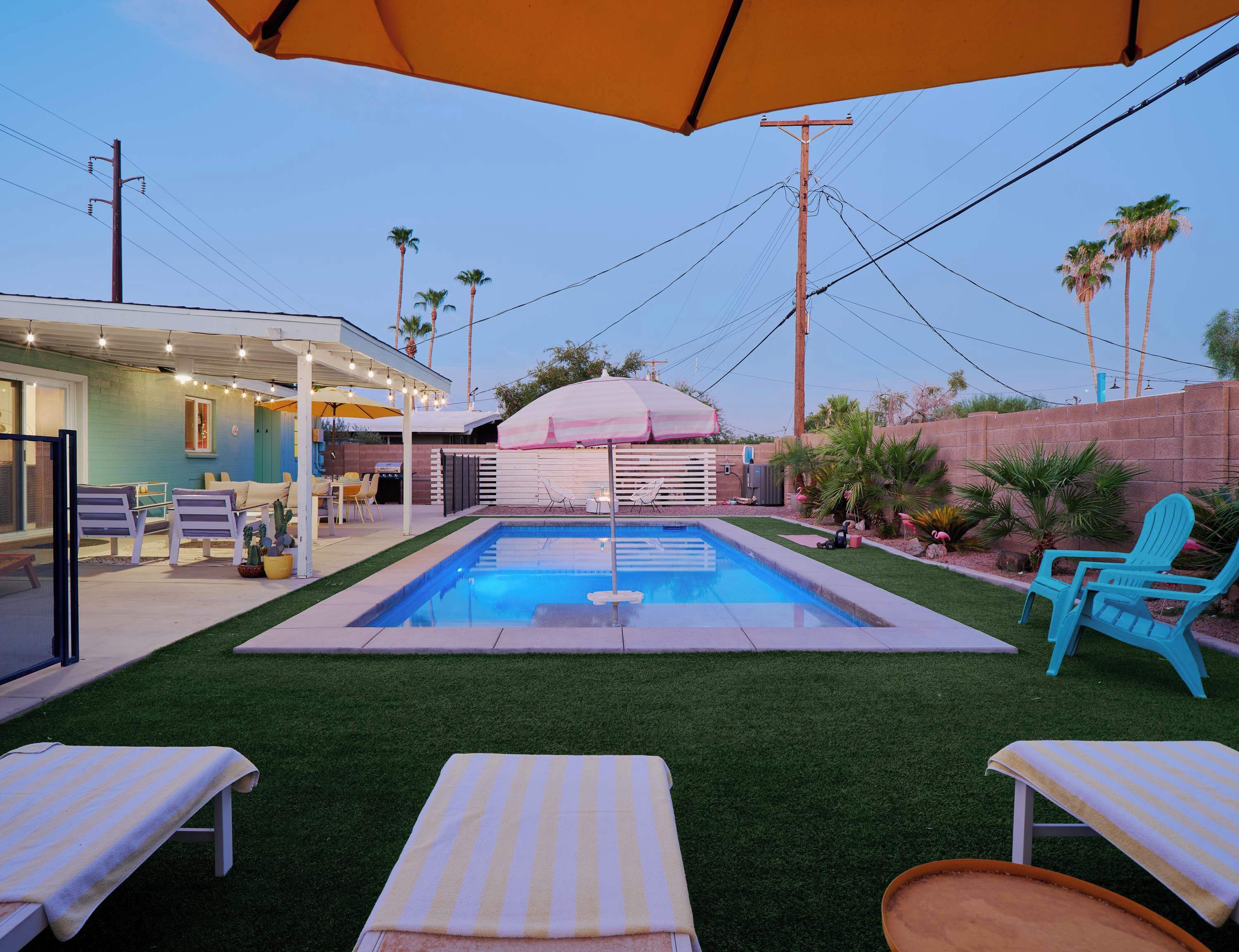 A backyard with a swimming pool, outdoor seating, and a covered patio area.