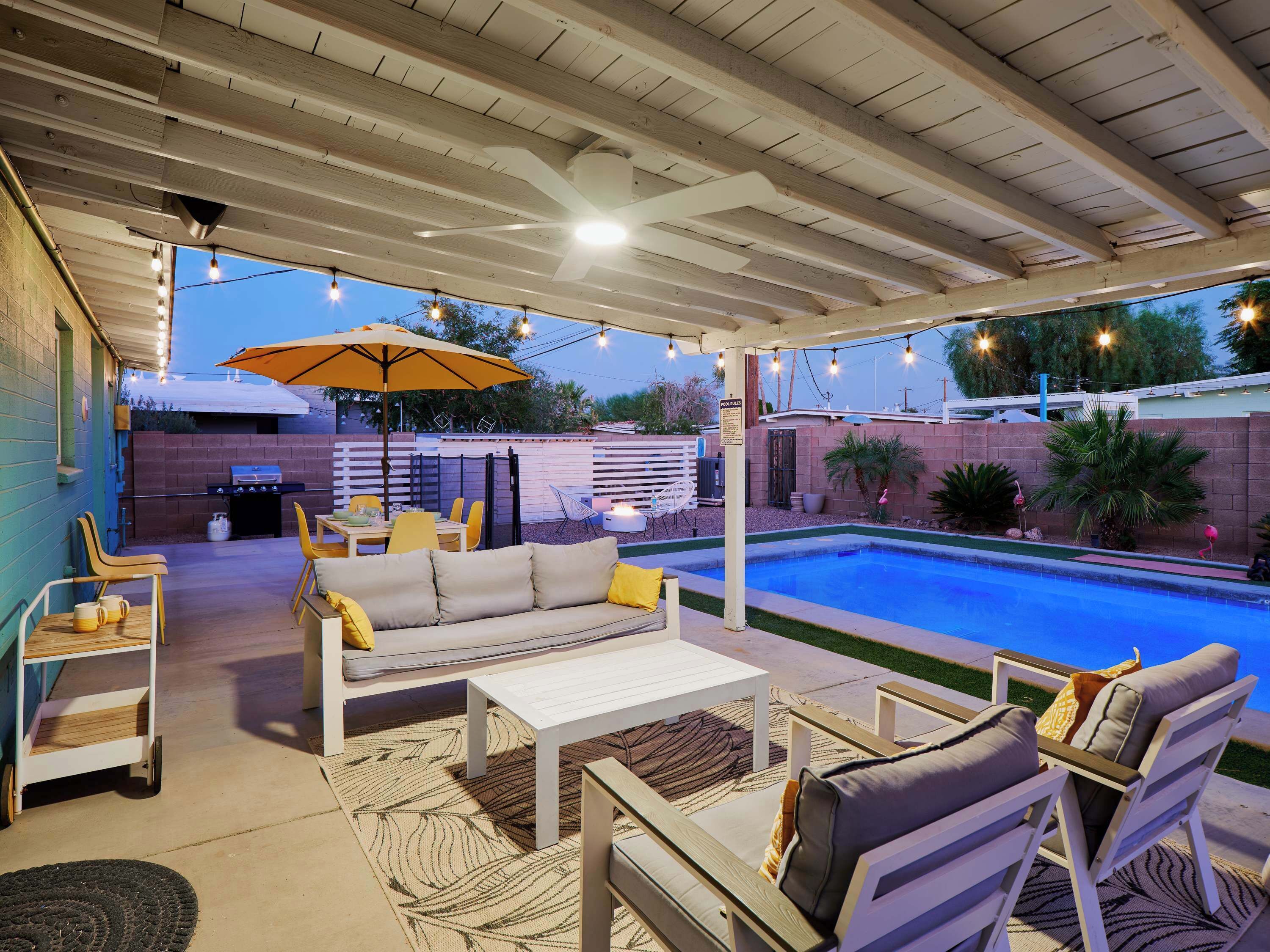 An outdoor patio with a pool, seating area, and barbecue grill.