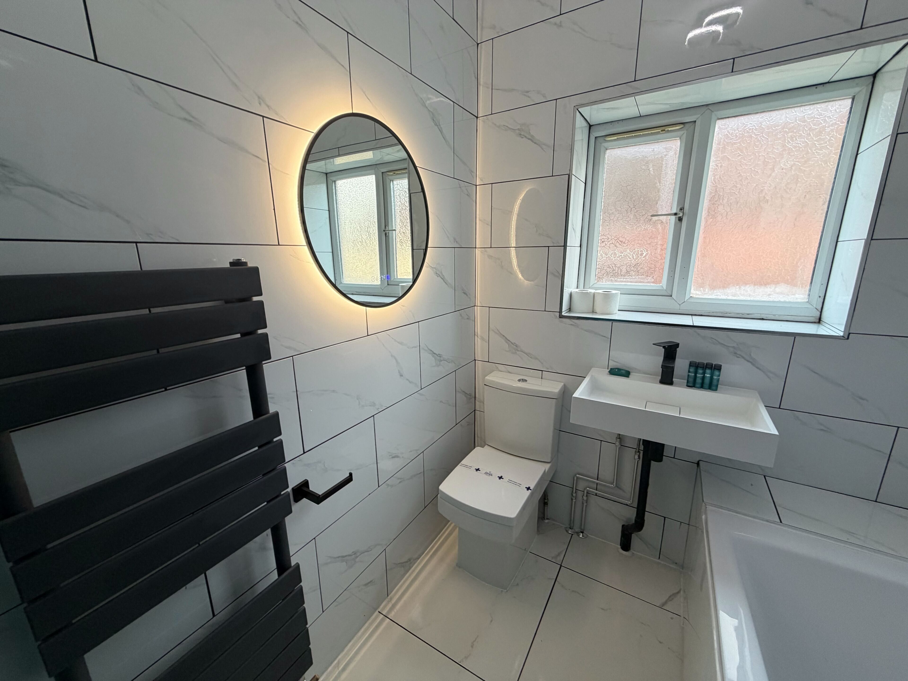A modern bathroom with a toilet, sink, and a window.