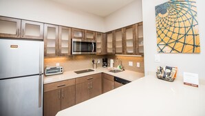 A modern kitchen with stainless steel appliances, wooden cabinets, and a large window. - Accessible 1BR Suite w/ Free Hot Breakfast + Pool (Humble)