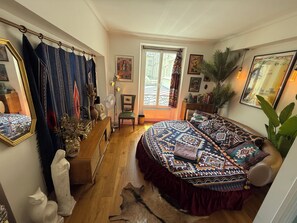 A bedroom with a large bed, a window, a mirror, and various decorations. - Retro and Rock 'n' Roll Room in Bastille! (Paris)