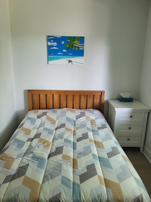 A bedroom with a bed, a nightstand, a drawer, and a wall-mounted painting of a beach scene. - Newly renovated suite, centrally located with full kitchen (Toronto)
