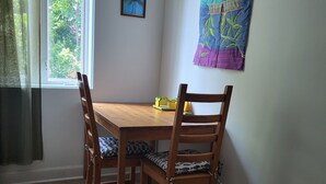 A dining area with a wooden table and chairs, a window with curtains, a wall tapestry, and a framed picture. - Newly renovated suite, centrally located with full kitchen (Toronto)