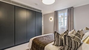 Um quarto com cama, janela e guarda-roupa.