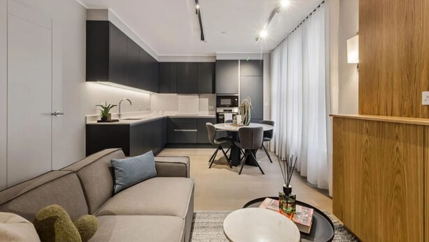 Uma sala de estar moderna com um sofá, uma mesa de centro e uma área de jantar com mesa e cadeiras.