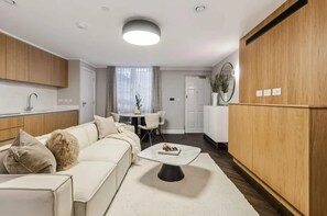 A modern living room with a sofa, coffee table, and dining area. - 7 Mins Walk to Selfridges Luxury Marble Arch Apt (London)