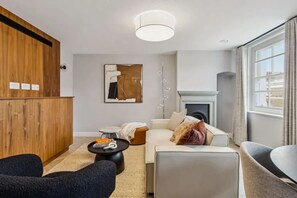 Ein modernes Wohnzimmer mit Kamin, einem Holzschrank, einem runden Couchtisch und einem Sofa.