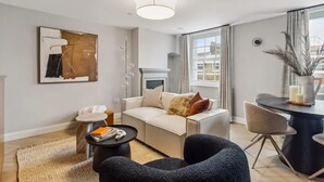 Ein modernes Wohnzimmer mit Sofa, Couchtisch, Beistelltisch, Sessel und einem Essbereich mit Tisch und Stühlen.
