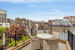 Eine Dachterrasse mit Korbmöbeln und Blick auf die Stadtlandschaft.