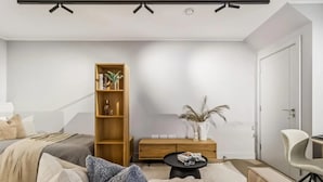 A modern living room with a sofa, a wooden bookshelf, a side table, and a white chair. - 9 Mins Walk to Selfridges Marble Arch Studio (London)