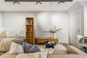 Ein modernes Wohnzimmer mit einer Couch, einem Holzregal, einem Beistelltisch und einem weißen Sessel.