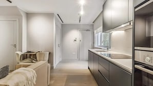 A modern kitchen with dark cabinetry, a countertop, and a built-in oven. - 9 Mins Walk to Selfridges Marble Arch Studio (London)