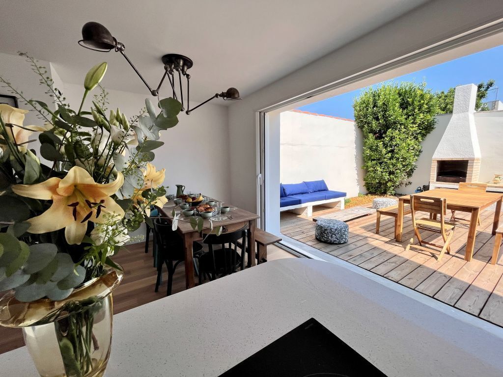 A modern kitchen with a dining area, a large window, and a view of the outdoors.