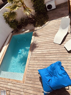 En træterrasse med en lille pool, liggestole og en blå pude.