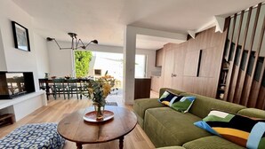 Una sala de estar moderna con un sofá verde, una mesa de comedor de madera y una zona de cocina.