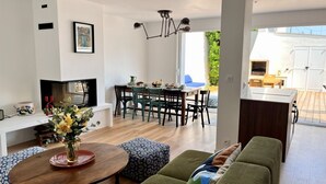 Una sala de estar moderna con un sofá, un comedor con sillas, un televisor y una chimenea.