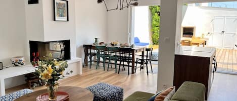 Un soggiorno moderno con un divano, un'area pranzo con sedie, una televisione e un caminetto.