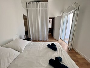 Et hotelværelse med en stor seng, et gardin, en skydedør og udsigt til gangen.