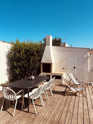 An outdoor patio with a brick oven, white chairs, and a table. - Superbe villa avec piscine à 10 min du centre (La Rochelle)